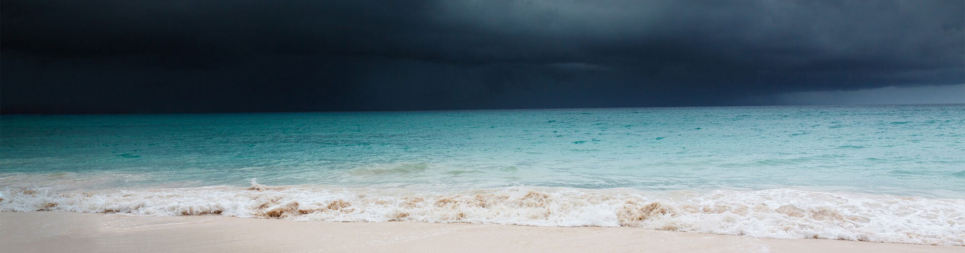 A hurricane looming in the distance over a beach.