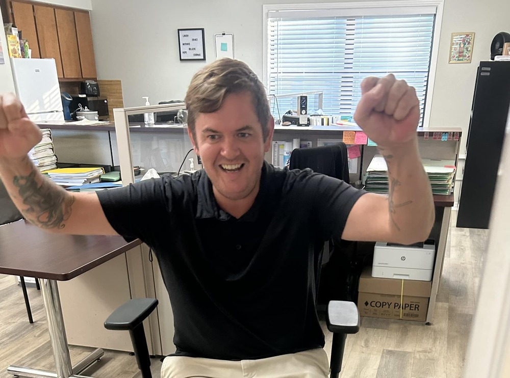 a man sitting down with his arms in the air, cheering and smiling