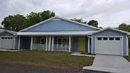 a blue house with a yellow door and white garage