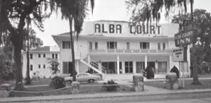 a two-story white building with large letters spelling Alba Court on the façade 