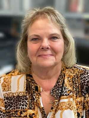 a blonde woman in an orange patterned shirt smiling