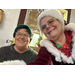 Mrs. Claus smiles next to a person in an elf hat