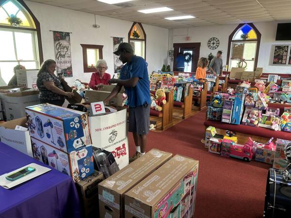 Workers organizing toys along the pews of a church