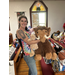 Woman standing in church full of toys hugging a giant wooly mammoth stuffed animal