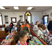 children and workers standing in a church filled with toys