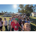 the group of kids outside posing for a group photo begin to disperse, running toward the camera and smiling