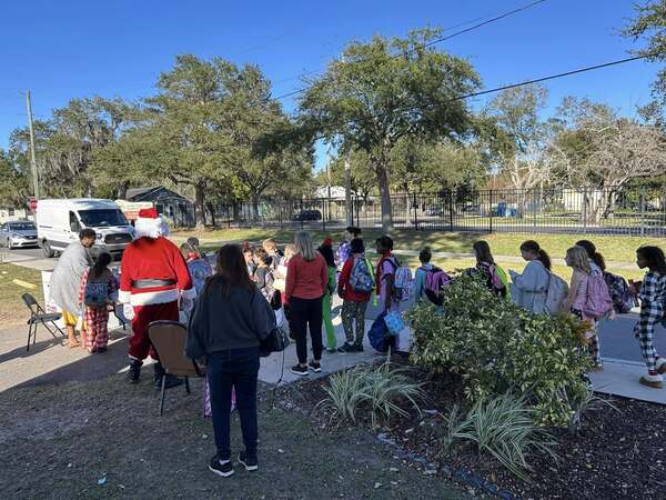 a line of children outside and Santa 